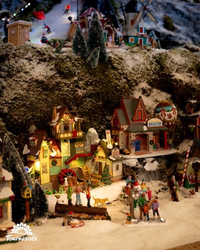 Scène miniature de village de Noël avec maisons illuminées et figurines.