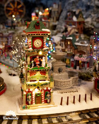 Village miniature de Noël avec horloge et décors lumineux.