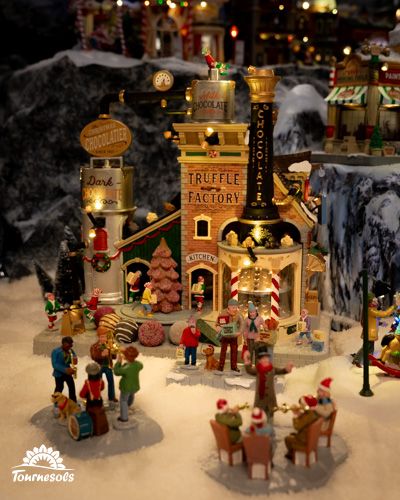 Scène d'un village miniature de Noël avec une chocolaterie animée.