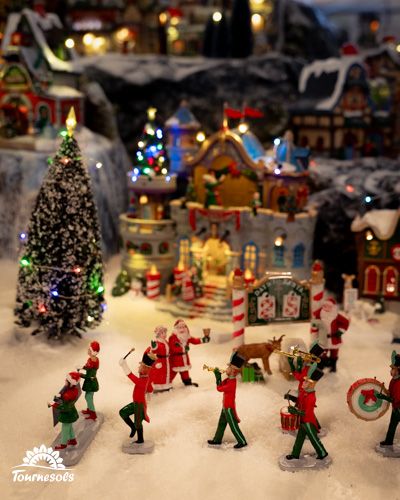Scène de village de Noël miniature avec personnages et décorations lumineuses.