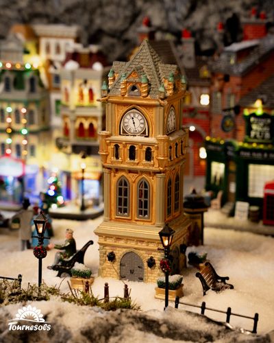 Village de Noël miniature avec tour horloge et maisons décorées.