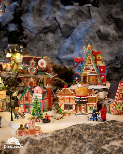 Village miniature de Noël avec maisons colorées et décorations enneigées.