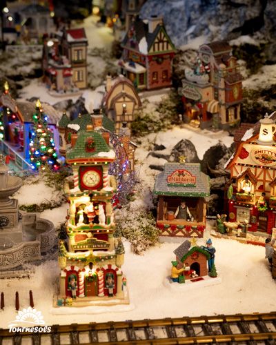 Village miniature de Noël avec maisons illuminées et décorations enneigées.