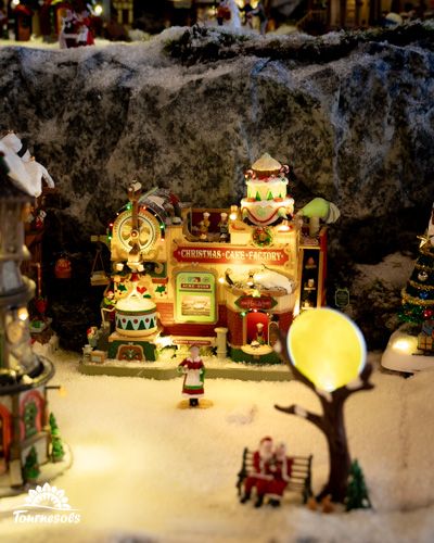 Village miniature de Noël avec une fabrique de bonbons lumineuse.