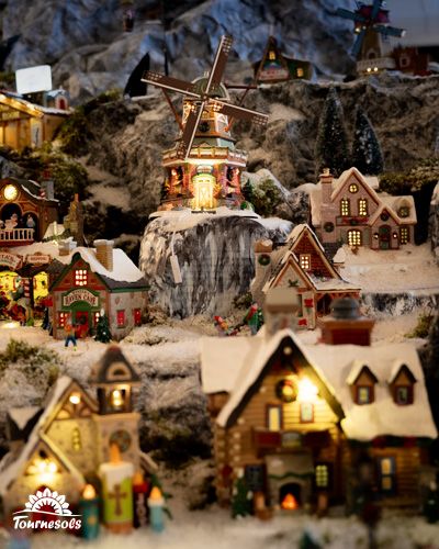 Village miniature Lemax avec maisons et moulin enneigés.
