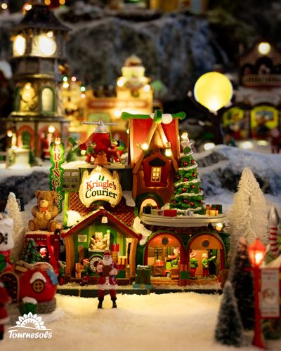 Village miniature Lemax avec maison illuminée, sapin et villageois en tenue de Noël.