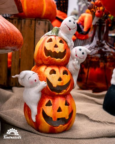 Citrouilles sculptées empilées avec des petits fantômes souriants.