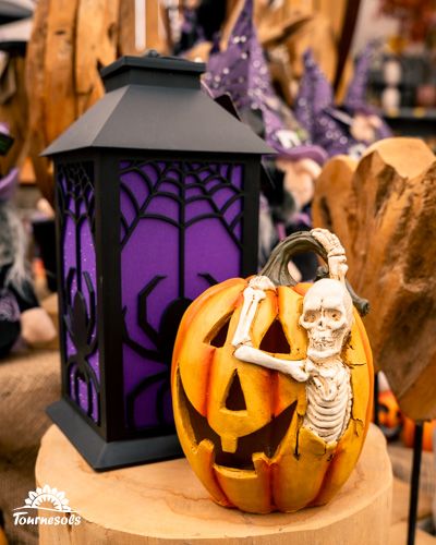 Citrouille sculptée avec squelette et lanterne décorative pour Halloween.
