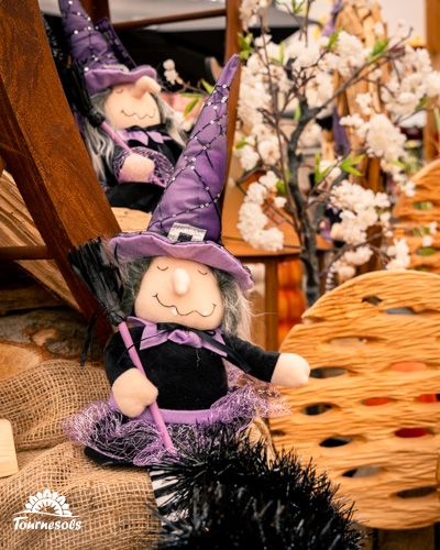 Petite sorcière en peluche dans un décor d'Halloween chez Tournesols.