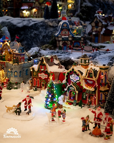 Village miniature Lemax enneigé avec maisons illuminées et scènes de Noël, proposé en déstockage à -50%.