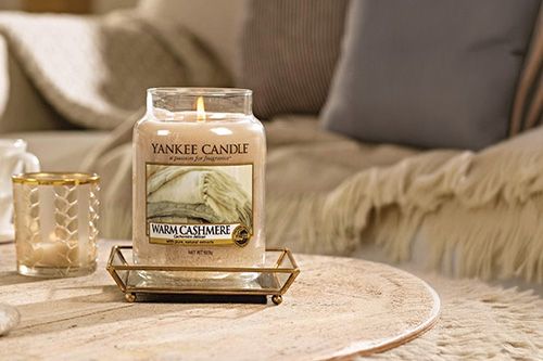 Bougie Yankee Candle allumée sur une table en bois.