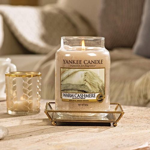 Bougie Yankee Candle Warm Cashmere allumée sur une table.