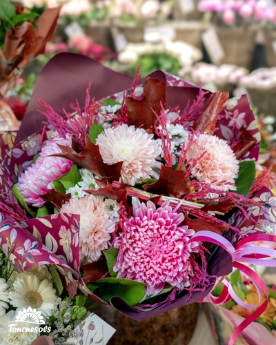 Bouquet de chrysanthèmes roses et blancs avec feuillages pourpres et rouges dans un emballage fleuri, en jardinerie