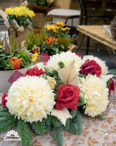 Composition de Toussaint avec chrysanthèmes crème, roses rouges, branches de sapin et palmes séchées en jardinerie