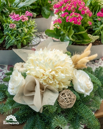 Composition de Toussaint avec chrysanthème crème, roses blanches et boule en rotin sur branches de sapin, chez Tournesols