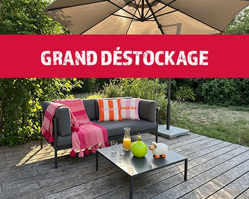 Salon de jardin sur une terrasse en bois sous un parasol, surplombé par une bannière rouge 
