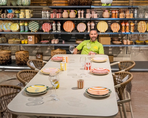 Responsable présentant une table dressée aux assiettes colorées dans le showroom de mars